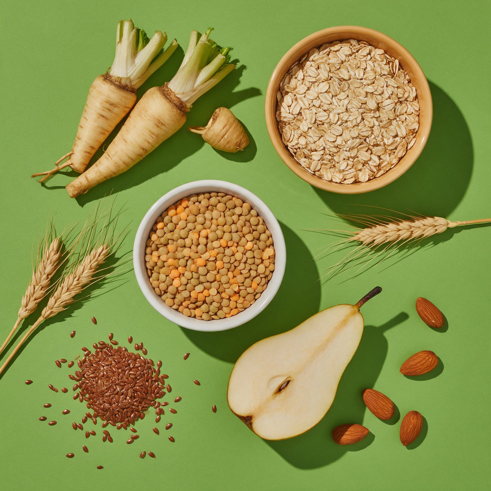 Raíz de achicoria, avena, lentejas, lino, espigas, pera y almendras sobre fondo verde